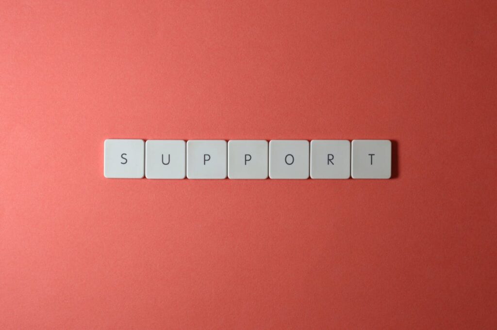 Close-up of the word 'support' spelled with keyboard keys on a red background.