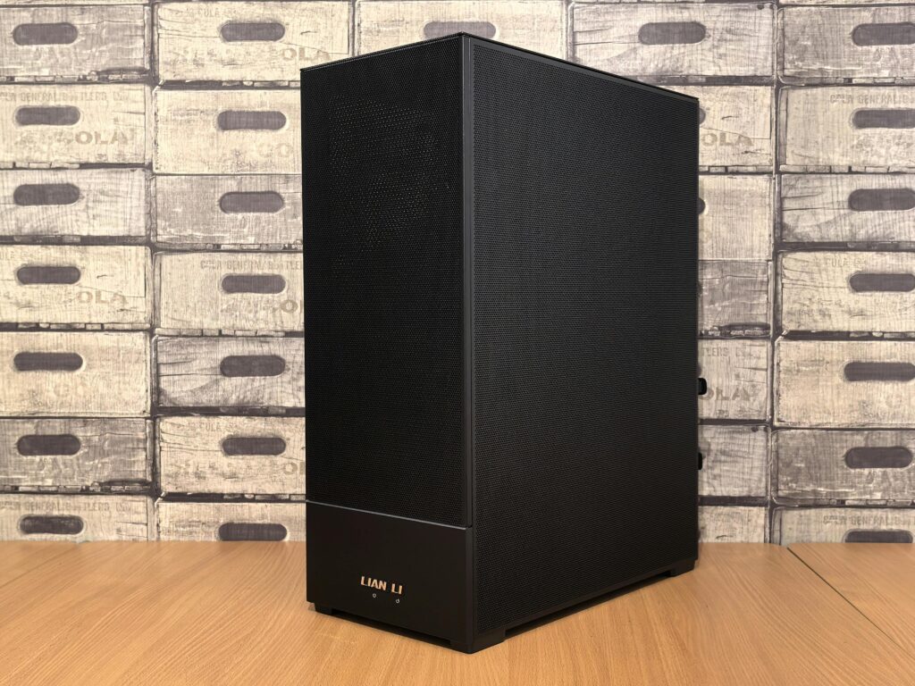 Black Lian Li computer case placed on a wooden desk with vintage box wallpaper background.